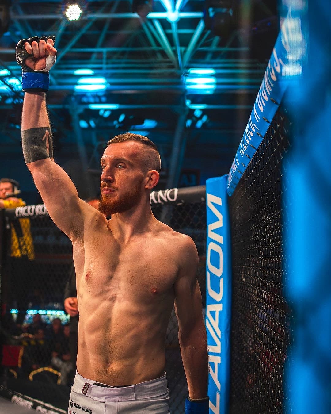 Jakub Dyk standing in the Oktagon ring, fist raised, moments before a fight